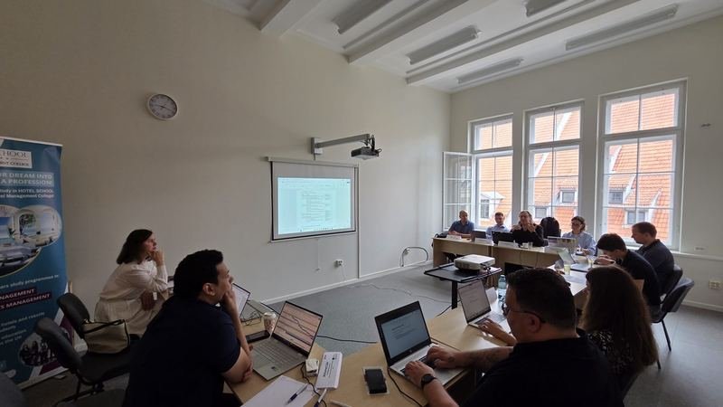 The partners following a presentation, with the old town roofs outside the windows
