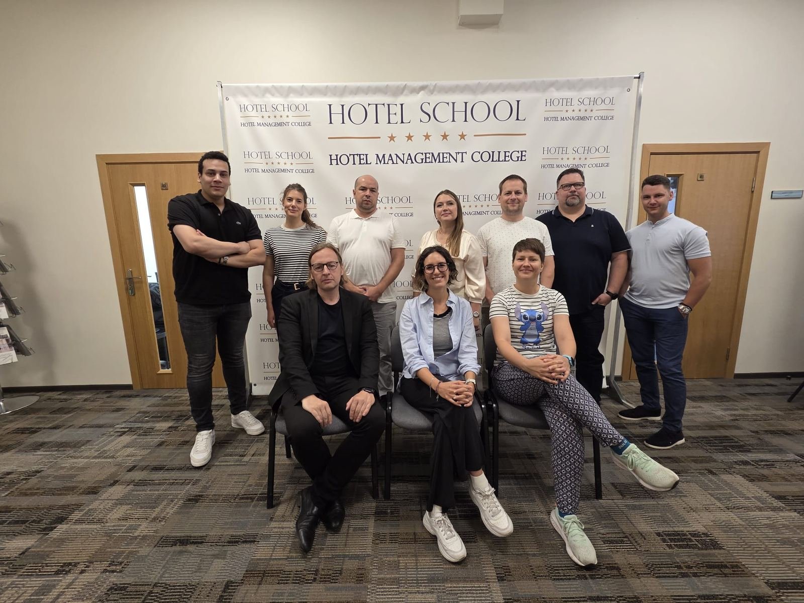 Group photo of the X-VET partners in front of the HOTEL SCHOOL banner in Riga